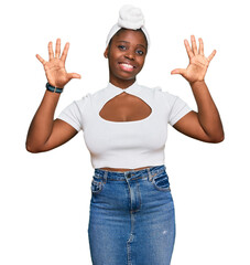 Canvas Print - Young african woman with turban wearing hair turban over isolated background showing and pointing up with fingers number ten while smiling confident and happy.