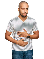 Poster - Hispanic adult man wearing casual clothes with hand on stomach because indigestion, painful illness feeling unwell. ache concept.