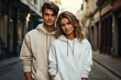 A trendy young couple wearing hoodies pose confidently on a city street, perfect for fashion, lifestyle, and urban relationship themes