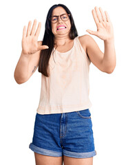 Sticker - Young beautiful caucasian woman wearing casual clothes and glasses afraid and terrified with fear expression stop gesture with hands, shouting in shock. panic concept.