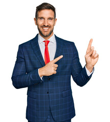 Canvas Print - Handsome man with beard wearing business suit and tie smiling and looking at the camera pointing with two hands and fingers to the side.