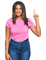 Sticker - Young latin girl wearing casual clothes showing and pointing up with finger number one while smiling confident and happy.