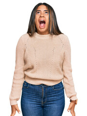 Canvas Print - Young latin girl wearing wool winter sweater angry and mad screaming frustrated and furious, shouting with anger. rage and aggressive concept.