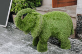 Fototapeta Dziecięca - An elephant, a beautiful sculpture made of green grass, a topiary bush stands on a city street. Photography, art concept, animal.