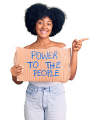 Poster - Young african american girl holding power to the people banner smiling happy pointing with hand and finger to the side