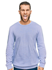 Poster - Young caucasian man wearing casual clothes sticking tongue out happy with funny expression. emotion concept.