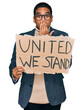 © Krakenimages.com - Young handsome hispanic man holding united we stand banner covering mouth with hand, shocked and afraid for mistake. surprised expression