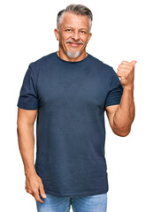 Poster - Middle age grey-haired man wearing casual clothes smiling with happy face looking and pointing to the side with thumb up.