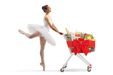 Wall Mural - Full length profile shot of a ballerina dancing and pushing a shopping cart with food and red ribbon bow