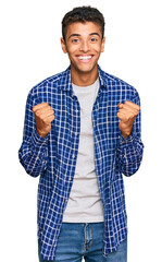 Canvas Print - Young handsome african american man wearing casual clothes celebrating surprised and amazed for success with arms raised and open eyes. winner concept.