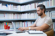 © Olena - Teacher with laptop in library classroom. Handsome teacher work on laptop in university library. Teachers Day. Teacher using laptop giving classes. School teacher hold laptop in library.