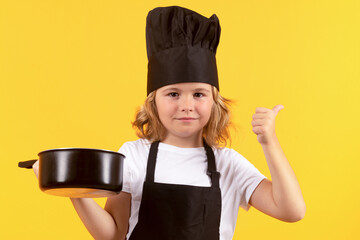 Wall Mural - Funny kid chef cook with kitchen pot stockpot. Child in cook uniform. Chef kid isolated on yellow background. Cute child to be a chef. Child dressed as a chef hat.