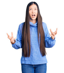 Sticker - Young beautiful chinese woman wearing casual turtleneck sweater crazy and mad shouting and yelling with aggressive expression and arms raised. frustration concept.