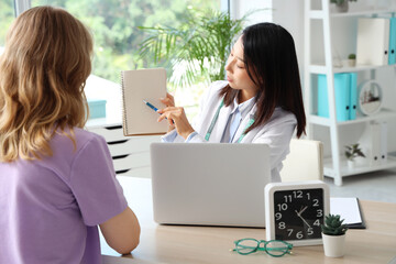 Canvas Print - Female Asian nutritionist working with patient in office