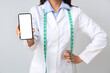Female nutritionist with mobile phone on light background, closeup