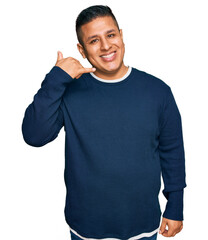 Poster - Young latin man wearing casual clothes smiling doing phone gesture with hand and fingers like talking on the telephone. communicating concepts.