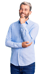 Wall Mural - Young handsome blond man wearing elegant shirt looking confident at the camera smiling with crossed arms and hand raised on chin. thinking positive.