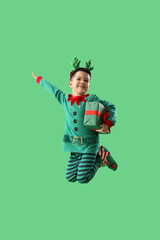 Wall Mural - Little Asian boy with Christmas gift jumping on green background