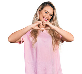 Sticker - Young blonde woman wearing casual pink t shirt smiling in love doing heart symbol shape with hands. romantic concept.