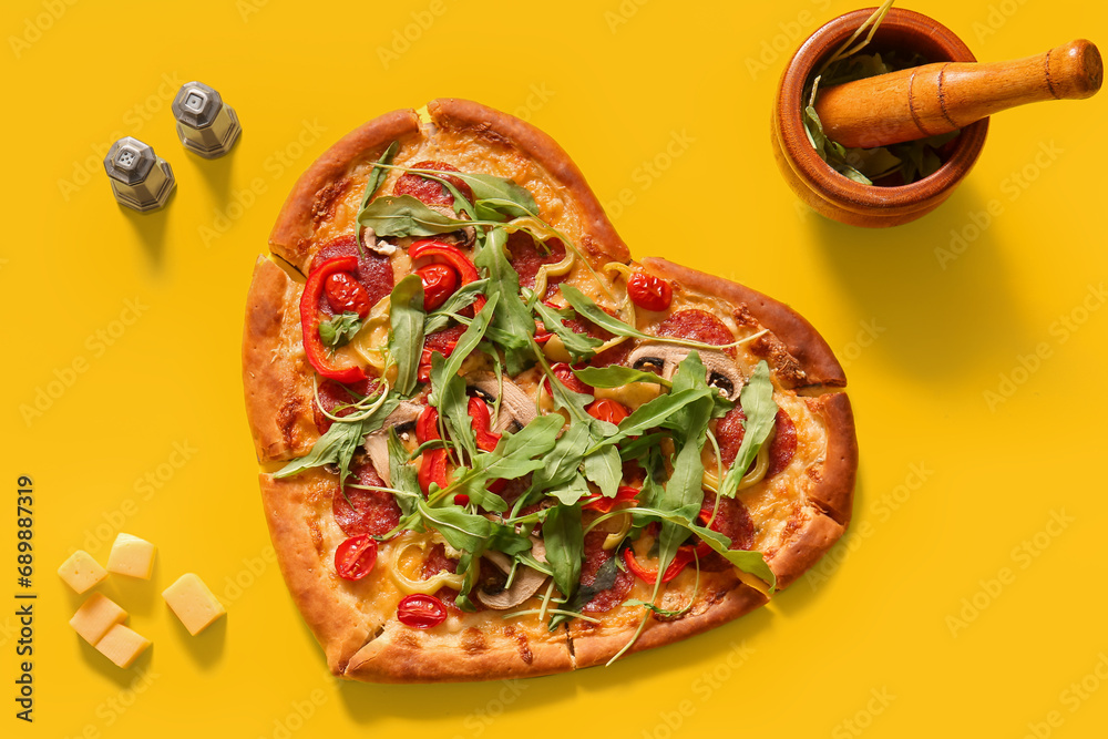 Tasty heart shaped pizza with arugula and cheese on yellow background