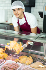 Male meat vendor provides selection of fresh, organic options at grocery store.