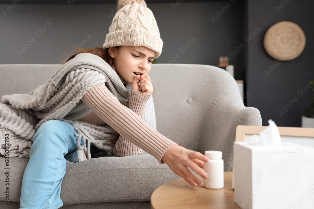 Sick little girl taking pill bottle at home