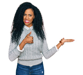 Wall Mural - Middle age african american woman wearing casual clothes showing palm hand and doing ok gesture with thumbs up, smiling happy and cheerful