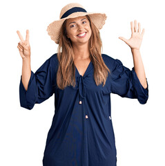 Canvas Print - Middle age hispanic woman wearing summer hat showing and pointing up with fingers number seven while smiling confident and happy.