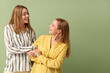 © Pixel-Shot - Beautiful young woman and her mother on green background. International Hug Day