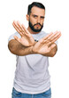 © Krakenimages.com - Young man with beard wearing casual white t shirt rejection expression crossing arms and palms doing negative sign, angry face