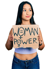 Wall Mural - Beautiful hispanic woman holding woman power banner smiling looking to the side and staring away thinking.