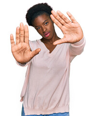Wall Mural - Young african american girl wearing casual clothes doing frame using hands palms and fingers, camera perspective