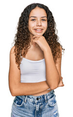 Wall Mural - Teenager hispanic girl wearing casual clothes looking confident at the camera with smile with crossed arms and hand raised on chin. thinking positive.