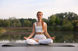 © New Africa - Beautiful young woman practicing Padmasana on yoga mat outdoors. Lotus pose