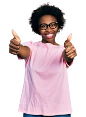 Sticker - African american woman with afro hair wearing casual clothes and glasses approving doing positive gesture with hand, thumbs up smiling and happy for success. winner gesture.