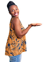 Sticker - Young african american woman wearing casual clothes pointing aside with hands open palms showing copy space, presenting advertisement smiling excited happy