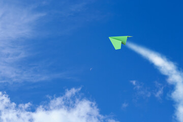 Canvas Print - Green paper plane flying in blue sky with clouds