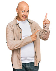 Wall Mural - Middle age bald man wearing casual clothes smiling and looking at the camera pointing with two hands and fingers to the side.