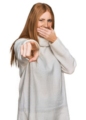 Wall Mural - Young irish woman wearing casual winter sweater laughing at you, pointing finger to the camera with hand over mouth, shame expression