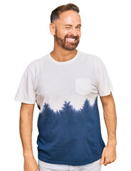 Poster - Handsome middle age man wearing casual tie dye tshirt winking looking at the camera with sexy expression, cheerful and happy face.