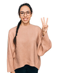 Wall Mural - Young hispanic girl wearing casual clothes and glasses showing and pointing up with fingers number three while smiling confident and happy.