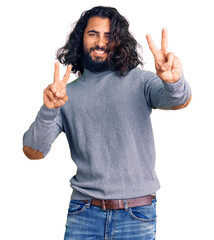 Young arab man wearing casual clothes smiling looking to the camera showing fingers doing victory sign. number two.