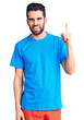 © Krakenimages.com - Young handsome man with beard wearing casual t-shirt pointing finger up with successful idea. exited and happy. number one.