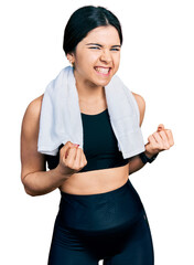 Wall Mural - Young brunette woman with blue eyes wearing sportswear and towel excited for success with arms raised and eyes closed celebrating victory smiling. winner concept.