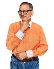 Poster - Middle age indian man wearing casual clothes and glasses with hand on chin thinking about question, pensive expression. smiling with thoughtful face. doubt concept.