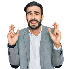 Canvas Print - Young hispanic man wearing business clothes gesturing finger crossed smiling with hope and eyes closed. luck and superstitious concept.