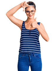 Sticker - Young beautiful woman wearing casual clothes and glasses smiling making frame with hands and fingers with happy face. creativity and photography concept.