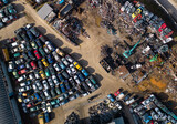 Fototapeta Uliczki - aerial view of a car dump, where a machine is seen separating old cars into scrap.