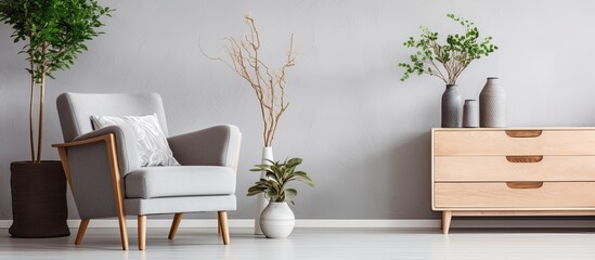 Sticker - Trendy Scandinavian living room with wooden commode, design armchair, carpet, leaf in vase, book, and personal accessories in unique home decor.