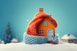 Winter orange house with a knitted hat and scarf on blue background